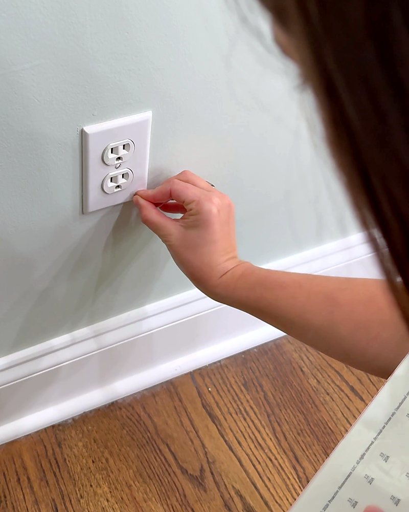 A woman pressing a Clear Label onto a receptacle cover